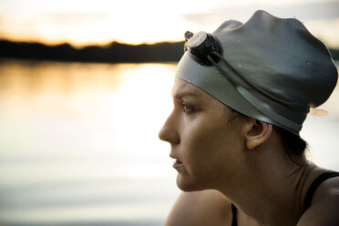 Close-up of thoughtful female swimmer sitting by lake - CAVF29142