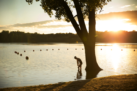 Female swimmer exercising in lake during sunset stock photo