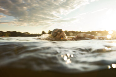 Schwimmerin schwimmt im See gegen den Himmel bei Sonnenuntergang - CAVF29149