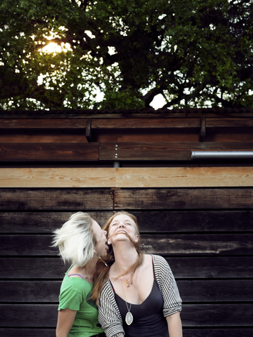 Glückliche Schwestern, die sich an einer Holzwand vergnügen, lizenzfreies Stockfoto