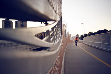 Mann radelt auf Brücke gegen klaren Himmel - CAVF29163
