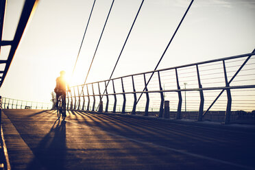 Mann radelt auf Brücke gegen klaren Himmel an sonnigem Tag - CAVF29168