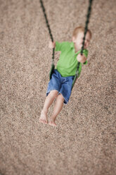 Hoher Blickwinkel des Jungen schwingt über Sand im Park - CAVF29182