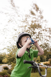 Junge fotografiert durch Kamera beim Radfahren im Park - CAVF29184