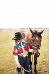 Mädchen stehend mit Pferd auf grasbewachsenem Feld gegen klaren Himmel - CAVF29185