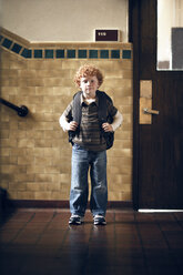 Portrait of boy carrying backpack while standing outside classroom - CAVF29192