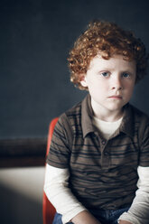 Portrait of boy sitting in front of blackboard at school - CAVF29194