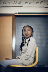 Low angle view of girl sitting on chair at classroom - CAVF29201