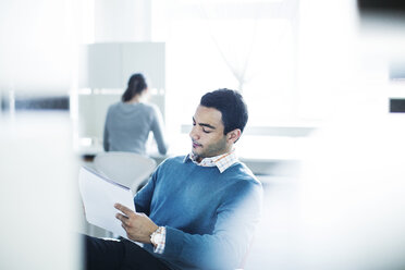 Seriöser Geschäftsmann, der ein Dokument liest, während er im Büro sitzt - CAVF29218