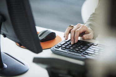 Cropped image of woman using computer keyboard at office desk - CAVF29230