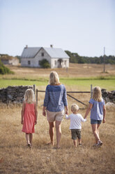 Mother with son and daughters walking in farm yard - FOLF01476