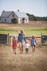 Mutter mit Sohn und Töchtern beim Spaziergang auf einem Bauernhof - FOLF01477