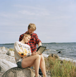 Couple using tablet pc at beach - FOLF01584