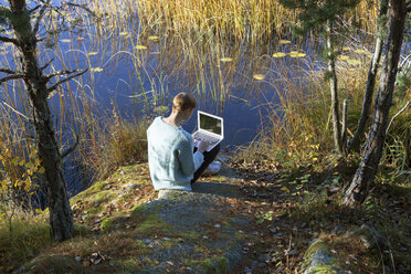 Frau benutzt Laptop am Seeufer - FOLF01590