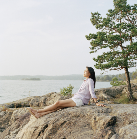 Mittlere erwachsene Frau entspannt sich am Strand, lizenzfreies Stockfoto