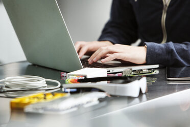 Mittelteil eines männlichen Studenten, der einen Laptop am Tisch benutzt - CAVF29316