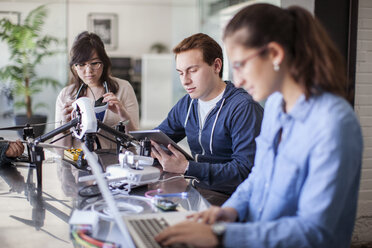 Freunde arbeiten mit elektrischen Geräten am Tisch im Klassenzimmer - CAVF29320