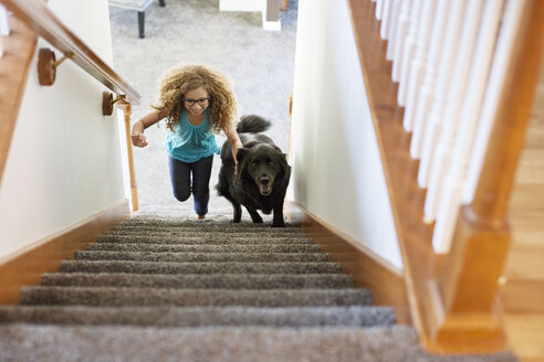 Hohe Winkel Ansicht von Mädchen mit Hund Klettern Treppe zu Hause - CAVF29329