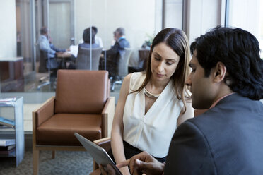 Businessman using tablet computer while discussing with colleague in office - CAVF29333