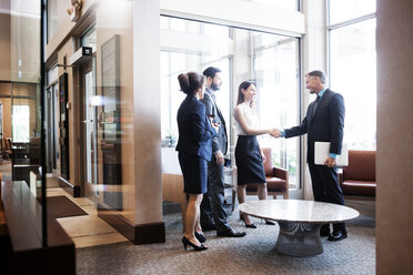 Business people shaking hands at office lobby - CAVF29346