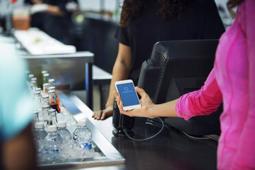 Ausgeschnittenes Bild einer Frau, die ihr Smartphone scannt, während sie im Restaurant ihre Rechnung bezahlt - CAVF29354