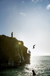 Freunde springen von einer Felsformation ins Meer - CAVF29368