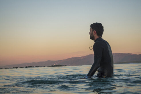 Seitenansicht eines männlichen Surfers im Meer gegen den klaren Himmel bei Sonnenuntergang - CAVF29390
