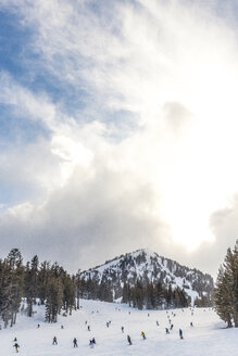Entfernte Ansicht von Skifahrern auf einem schneebedeckten Berg gegen einen bewölkten Himmel - CAVF29399