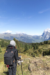 Rückansicht eines Wanderers mit Rucksack auf einem Berg vor blauem Himmel - CAVF29411