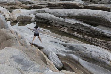 Rear view of female hiker walking on rocks - CAVF29416