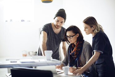 Business people looking at laptop in cafeteria - CAVF29440