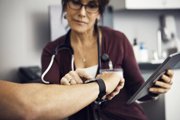 Ärztin, die in einer Klinik die Zeit auf der Armbanduhr eines Patienten überprüft - CAVF29531