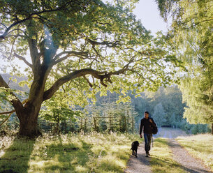Mann geht mit Hund spazieren - FOLF01694