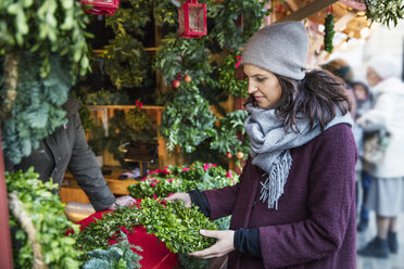 Frau sucht Weihnachtskranz auf dem Markt aus - FOLF01854