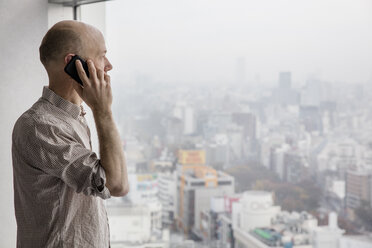 Man talking on phone and looking through window - FOLF01868