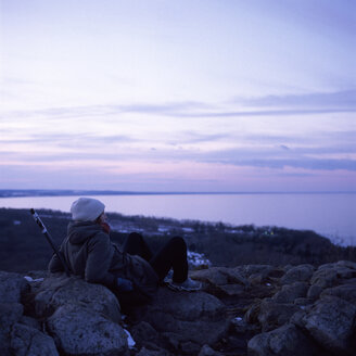 Frau sitzt auf Steinen und beobachtet das Meer - FOLF01998
