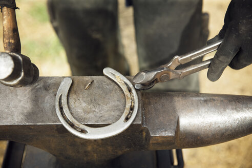 Mittelteil eines Hufschmieds bei der Herstellung eines Hufeisens auf dem Amboss - CAVF29575