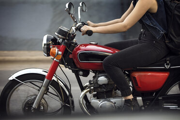 Low section of woman riding motorcycle on road - CAVF29584