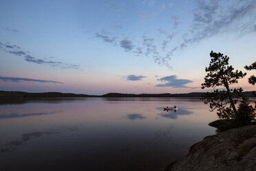 Menschen, die in einem Boot auf einem ruhigen See gegen den Himmel bei Sonnenuntergang fahren - CAVF29586