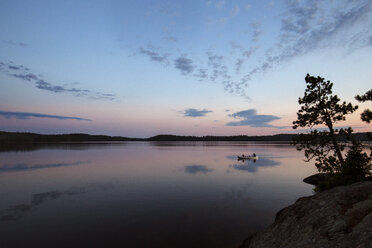 People traveling in boat on calm lake against sky during sunset - CAVF29586