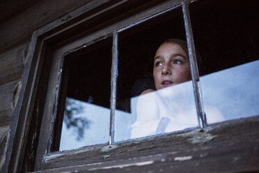 Low angle view of thoughtful girl looking through window seen through glass - CAVF29588