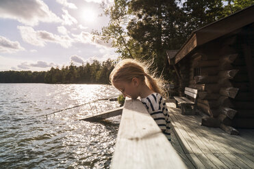 Side view of girl standing by railing over lake during sunny day - CAVF29592