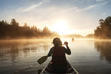 Rear view of woman traveling in boat on lake - CAVF29594