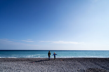 Rückansicht einer älteren Frau, die mit einem Mädchen am Strand steht, gegen den Himmel - CAVF29621