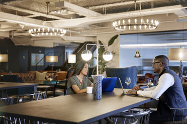 Geschäftsleute, die Laptops benutzen, während sie im Kreativbüro sitzen - CAVF29700