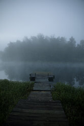 Wooden pier over lake against trees and sky during foggy weather - CAVF29723