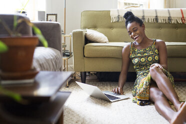 Happy woman using laptop computer at home - CAVF29732