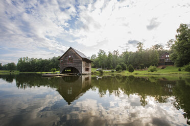 Wooden house on lake against cloudy sky - CAVF29754