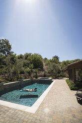 Woman relaxing on pool raft at swimming pool - CAVF29757