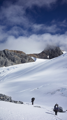 Männer wandern auf schneebedecktem Berg gegen den Himmel, lizenzfreies Stockfoto